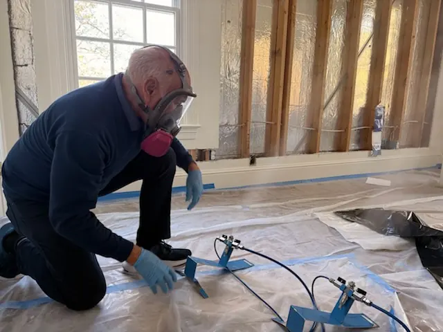 A restoration technician setting drying equipment in a Cary home stripped to the studs